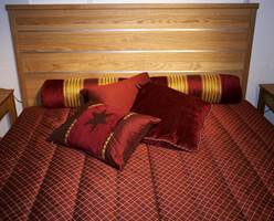 Et gjennomført sammensatt sengesett på soverommet - i de skinnende tekstiler. Sengen er av eik. (Fra CS Möbelfabrik)