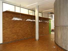 Mosaikkparketten er brukt også på vegg i garderoben, i kontrast til betongsylinderen som går over flere etasjer og inneholder fellesarealer.