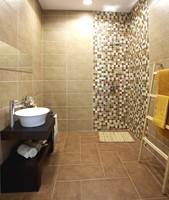 Store fliser på gulv og vegg, kombinert med mosaikkflis i dusjhjørnet, i beige- og bruntoner.