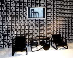 Sorte designmøbler kombinert med retromønster i sort-hvitt og flatskjerm på vegg. (Finsk design)