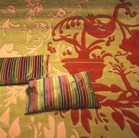 Igjen de kraftige mønstre på teppet i flotte, sammensatte jordfarger, matchende med puter i de like typiske blanke tekstiloverflater. Stripemønster er en gjenganger.