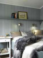 En hyggelig sengeplass! Dempete, freshe farger skaper en innbydende atmosfære, sammen med sengetøy og saueskinn. 