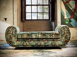 KONTRAST: En sofa trukket med tekstil fra Aldeco poserer i rustikke omgivelser, der teppet er en spennende kontrast til omgivelsene.