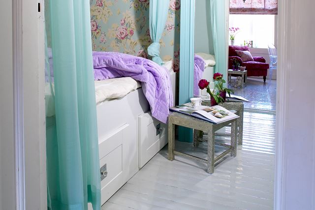 Lys turkisfarge illuderer både frisk luft og lys. Flortynne gardiner gir rommet et svalt inntrykk og skjermer samtidig sengen. 