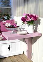 Et lite, snertent bord, malt i rosa. Det kan slås ned når det ikke er i bruk. 