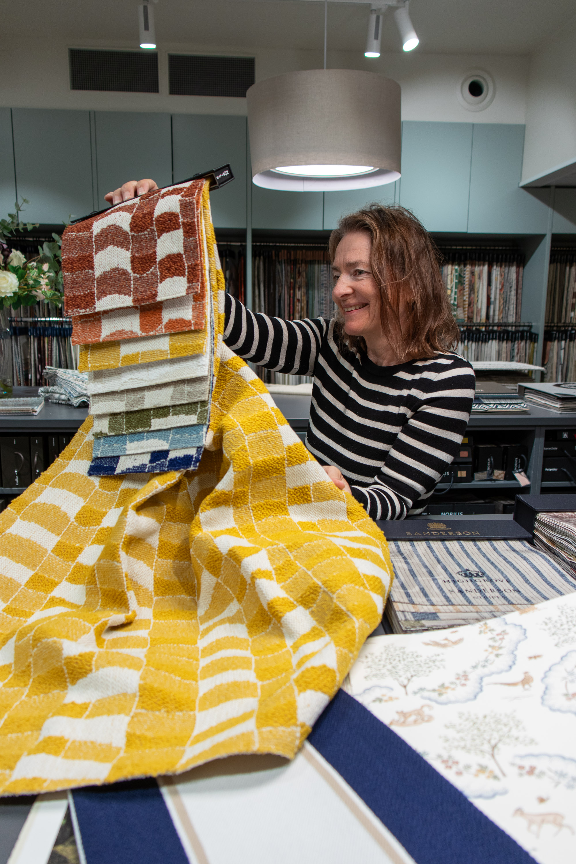 dame holder opp prøver på tekstil som kan brukes ute og inne 