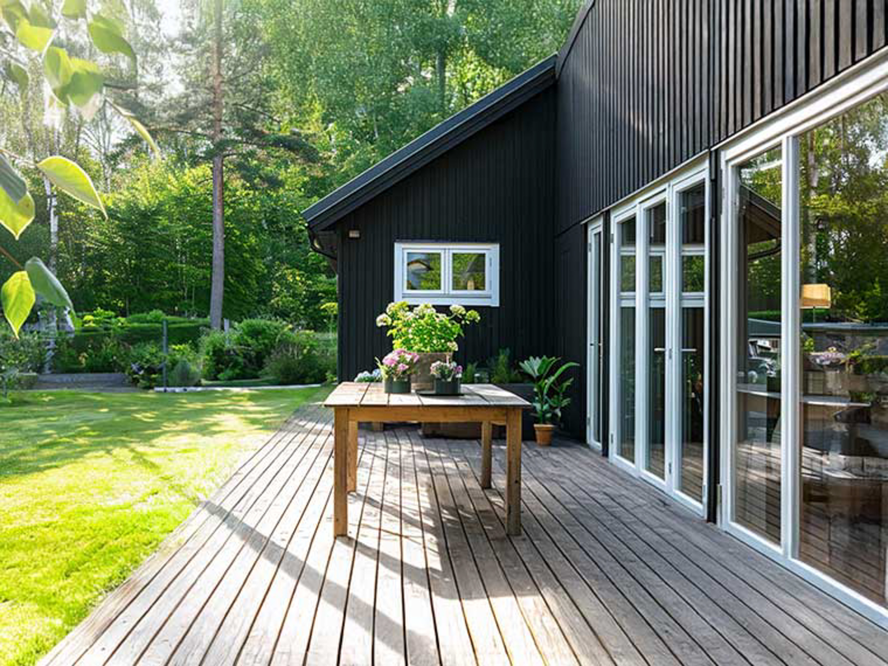 treplatting med spisebord på, ved et sortmalt hus med trefasade
