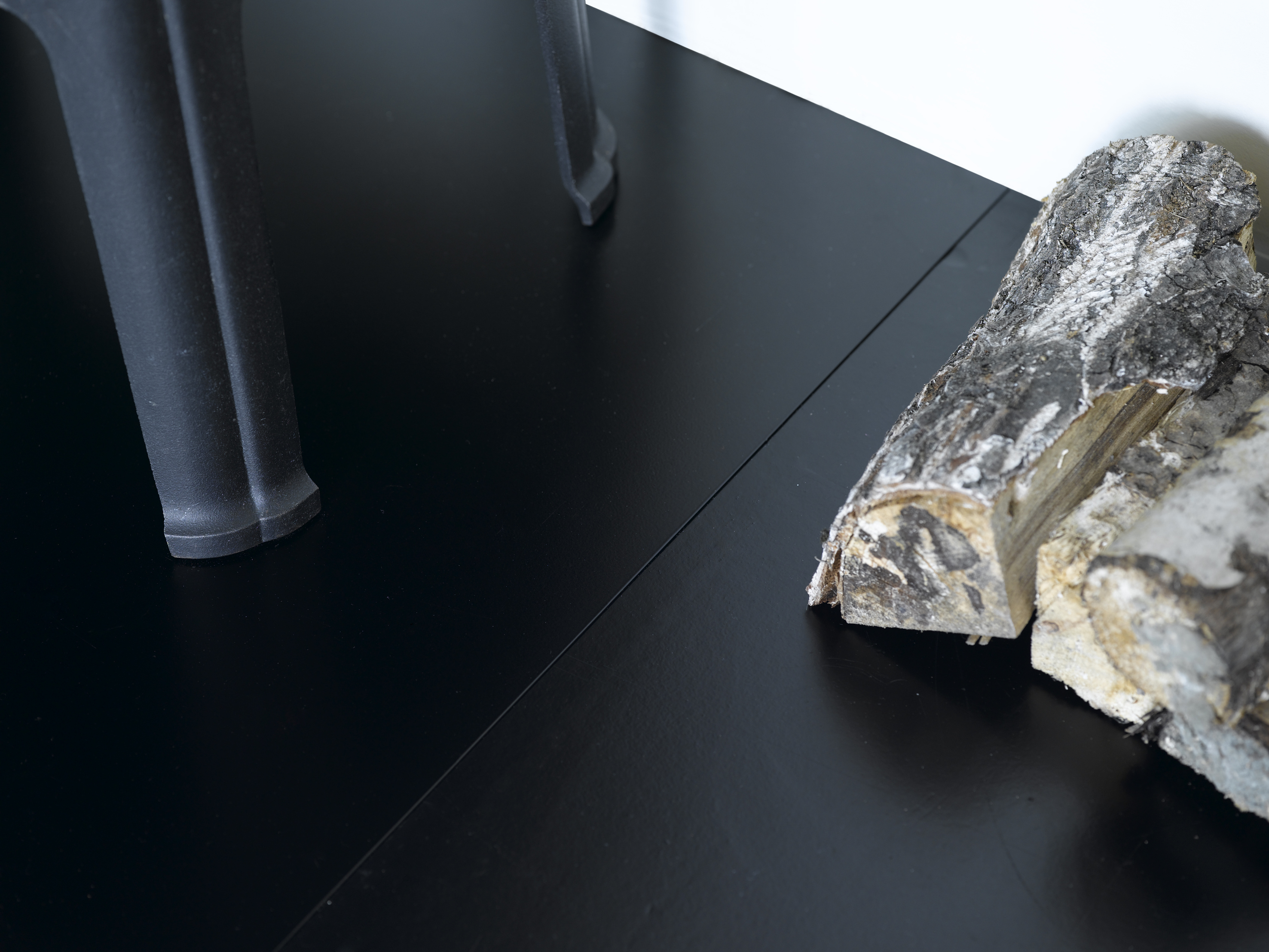 Den sorte stålplaten under ovnen går i ett med det sortmalte gulvet. 